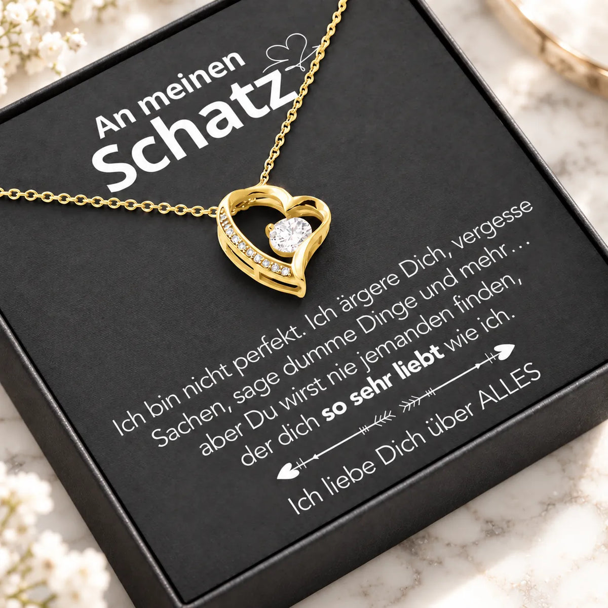Gelbgold-Herzanhänger auf Karte An meinen Schatz in schwarzer Premium-Box, schräge Nahaufnahme auf hellem Marmor
