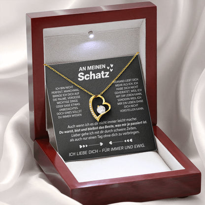 Gelbgold-Herzanhänger auf der Karte An meinen Schatz in der geöffneten Mahagoni-Box mit LED-Licht, auf weißem Satin