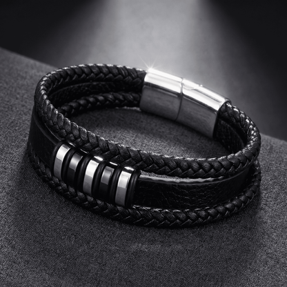 Lederarmband mit Silberverschluss und schwarzen Zwischenringen, Nahaufnahme vor dunklem Stoffhintergrund