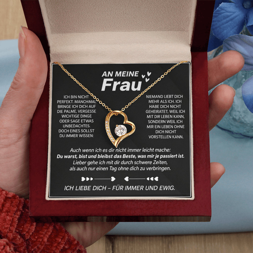 Hand hält die geöffnete Mahagoni-Box mit Gelbgold-Herzanhänger auf der Karte An meine Frau