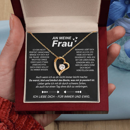 Hand hält die geöffnete Mahagoni-Box mit Gelbgold-Herzanhänger auf der Karte An meine Frau