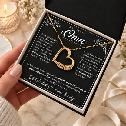 Hände halten die geöffnete Premium Box mit Gelbgold-Familienherz auf der Karte An meine Oma
