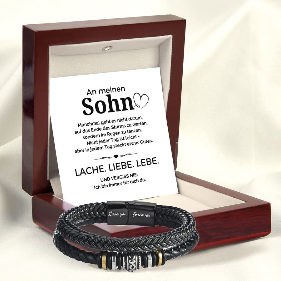Geöffnete Mahagonibox mit der Karte An meinen Sohn, das Lederarmband liegt auf cremefarbenem Samtkissen davor