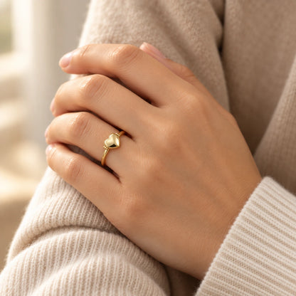 Goldener Herz-Medaillonring an der Hand getragen