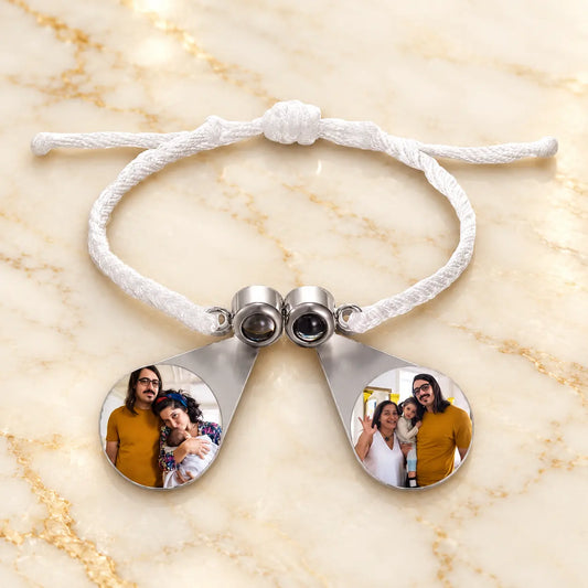 Weißes geflochtenes Fotoarmband mit silberner Perlenspange und zwei runden Bildanhängern auf hellem Marmor