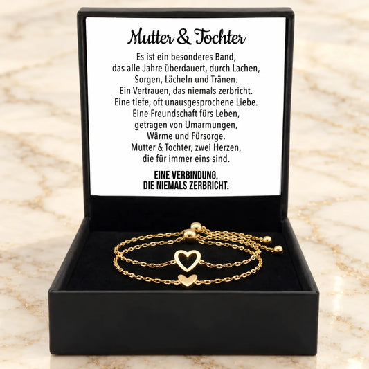 Zwei goldene Herz-Armbänder liegen in einer offenen Geschenkbox neben der Gedichtkarte für Mutter und Tochter.