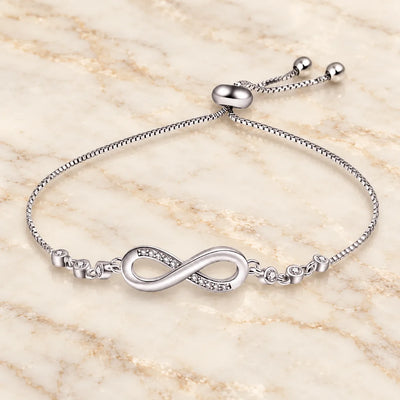 Silbernes Unendlichkeits-Armband mit Zirkonia-Steinen und verstellbarem Verschluss auf hellem Marmor
