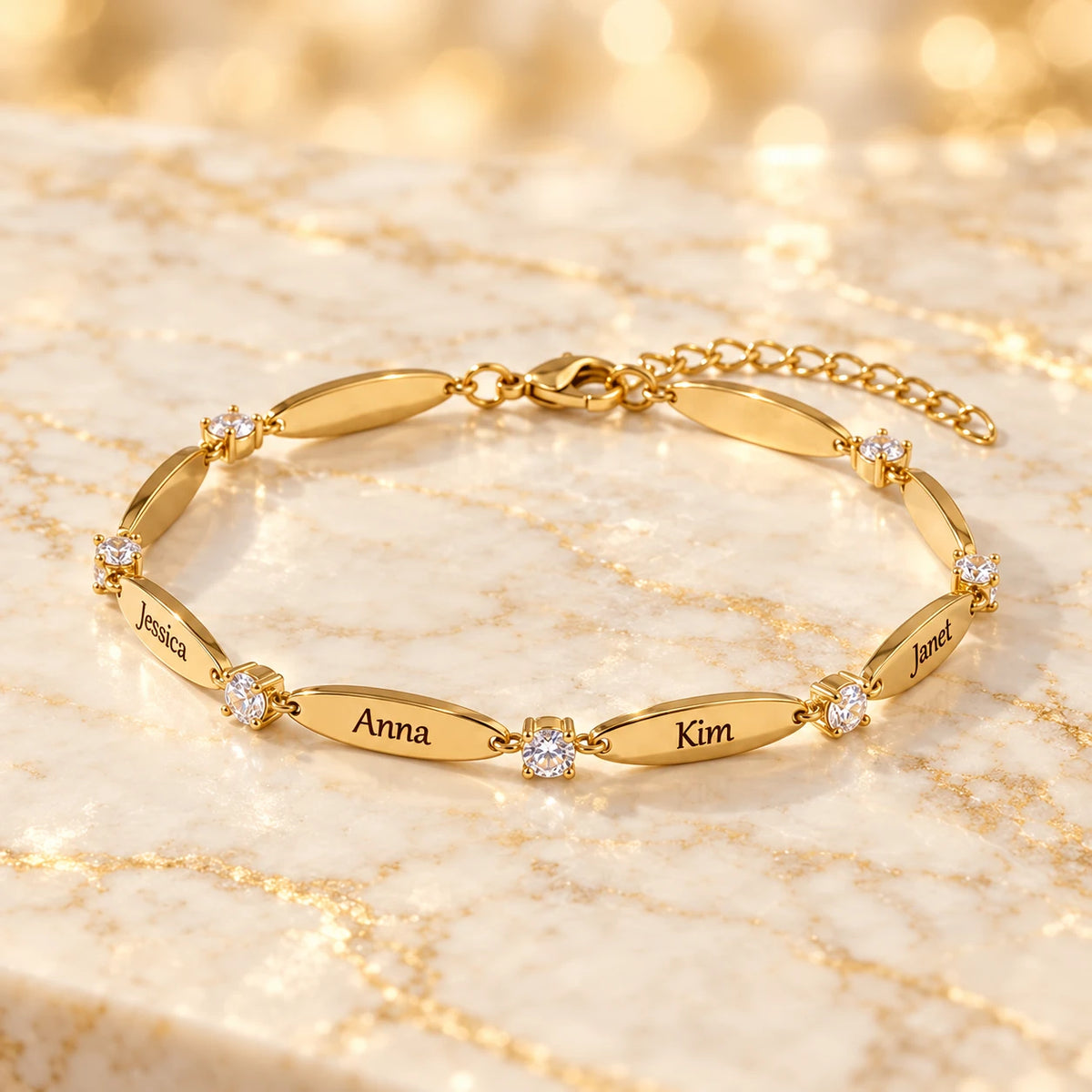 Gelbgold-Armband mit gravierten Namen Jessica, Anna, Kim und Janet und Zirkonia-Steinen auf hellem Marmor