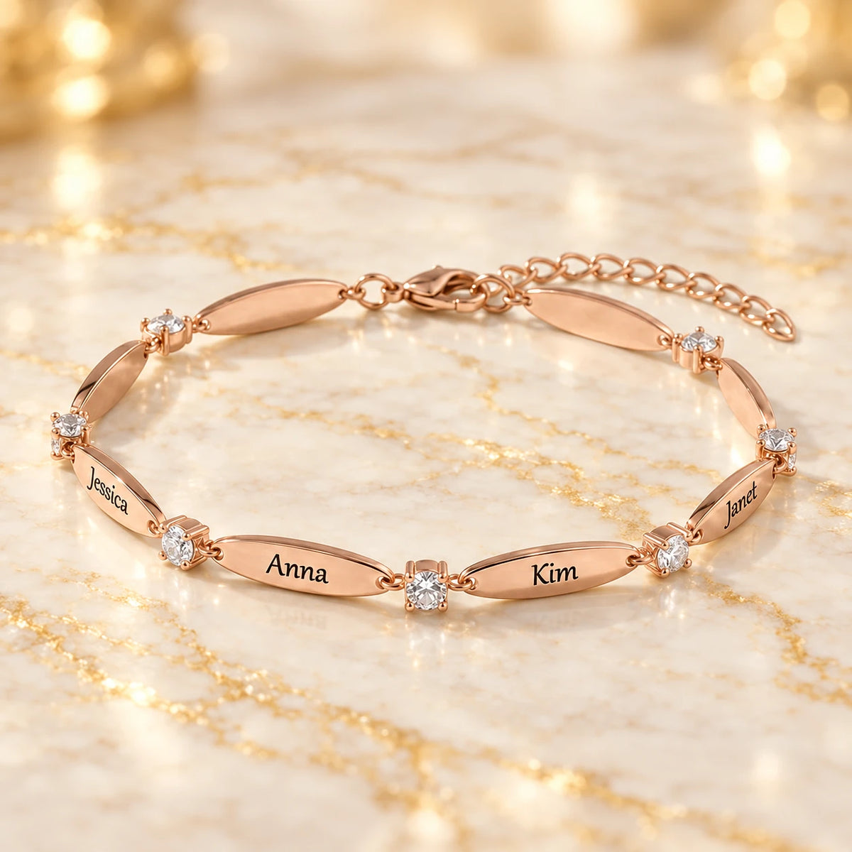 Roségold-Armband mit gravierten Namen Jessica, Anna, Kim und Janet und Zirkonia-Steinen auf hellem Marmor