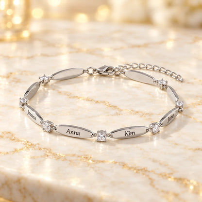 Weißgold-Armband mit gravierten Namen Jessica, Anna, Kim und Janet und Zirkonia-Steinen auf hellem Marmor