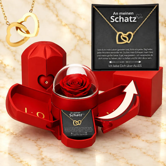 Geöffnete rote Rosenbox mit Rose unter Glaskuppel, daneben goldene Doppelherz-Kette auf der Karte An meinen Schatz
