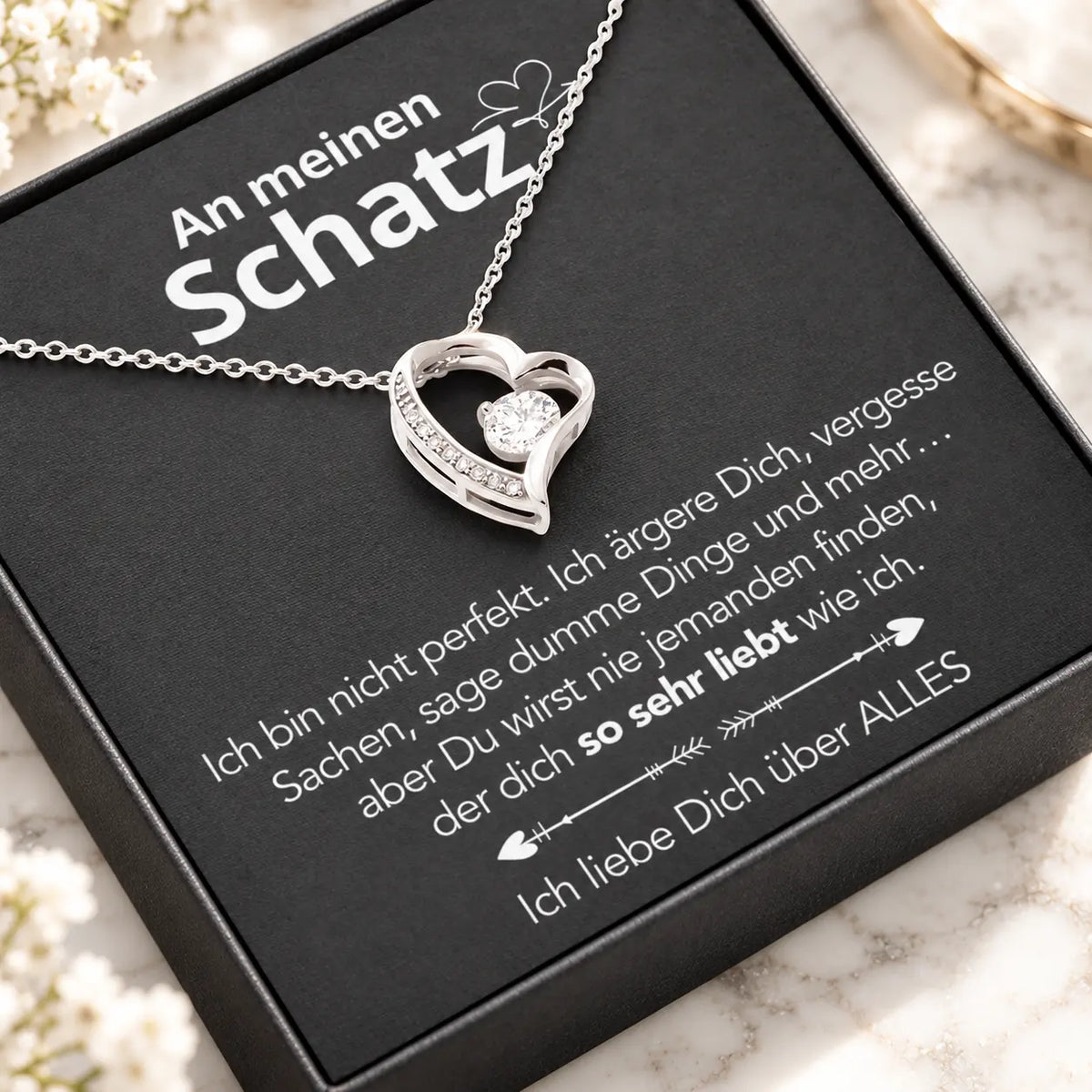 Weißgold-Herzanhänger auf Karte An meinen Schatz in schwarzer Premium-Box, schräge Nahaufnahme auf hellem Marmor
