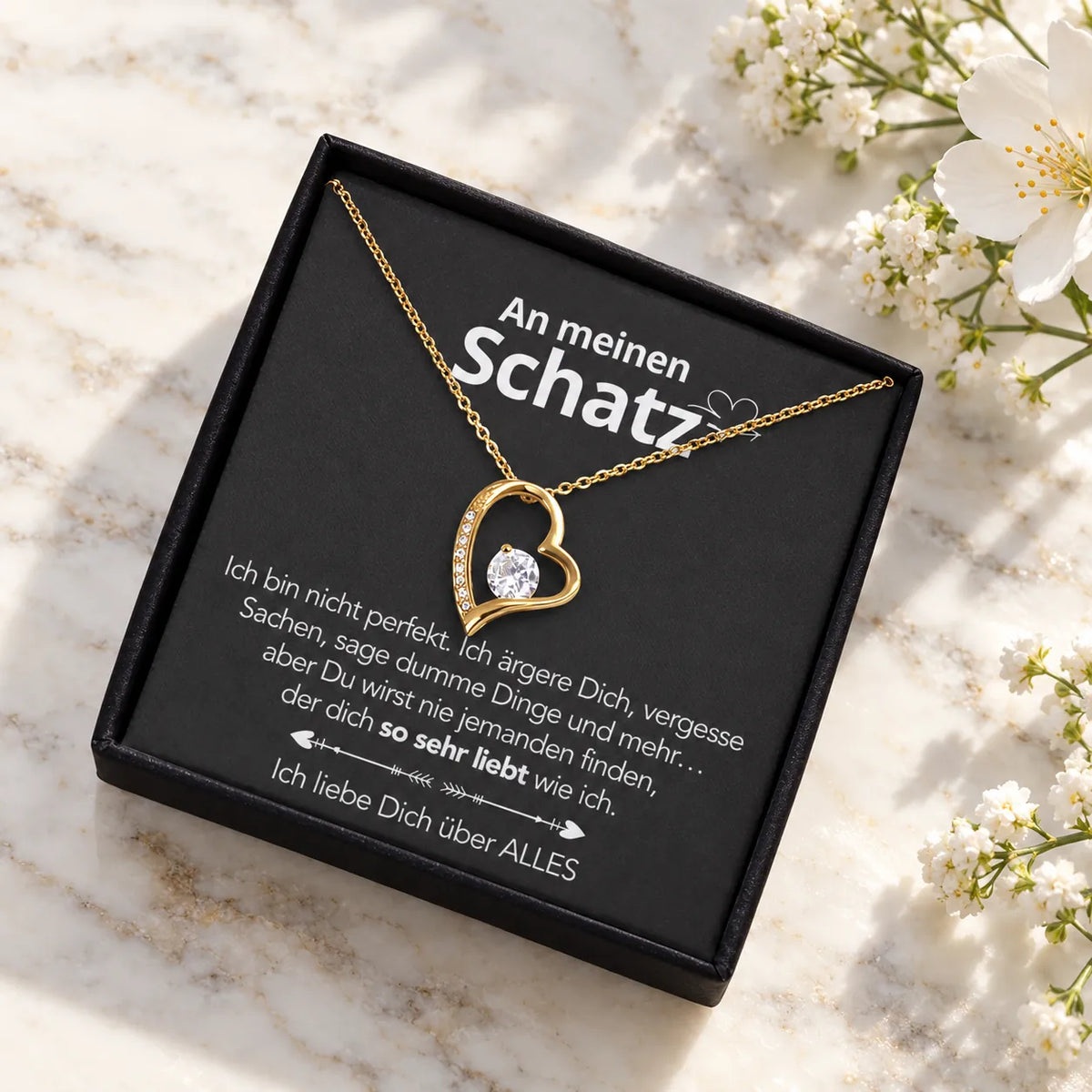 Gelbgold-Herzanhänger auf Karte An meinen Schatz in schwarzer Premium-Box auf hellem Marmor