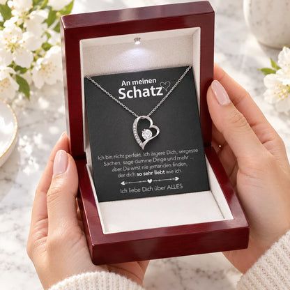Weißgold-Herzanhänger mit Karte An meinen Schatz in Mahagoni-Box als Geschenk in den Händen