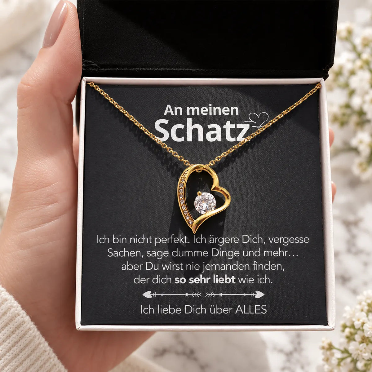 Gelbgold-Herzanhänger mit Karte An meinen Schatz in schwarzer Geschenkbox in der Hand